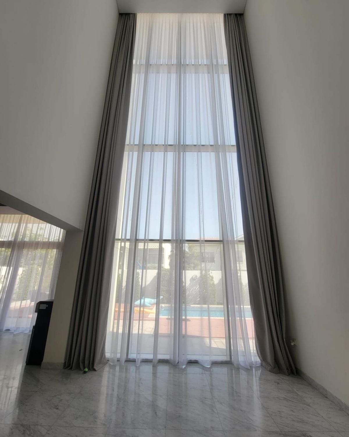 Floor-to-ceiling sheer curtains in a double-height living room